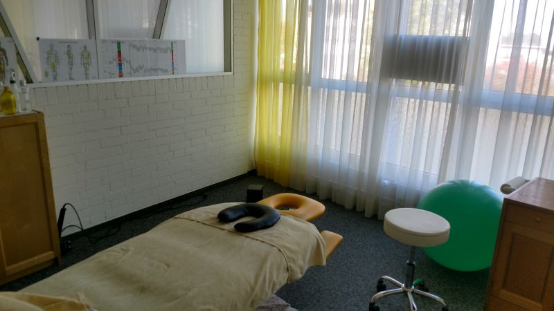 Behandlungsraum mit Liege, Hocker und Fenster